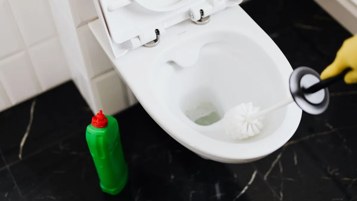 Cuvette de WC bouchée avec eau stagnante, salle de bains carrelée, vue réaliste.