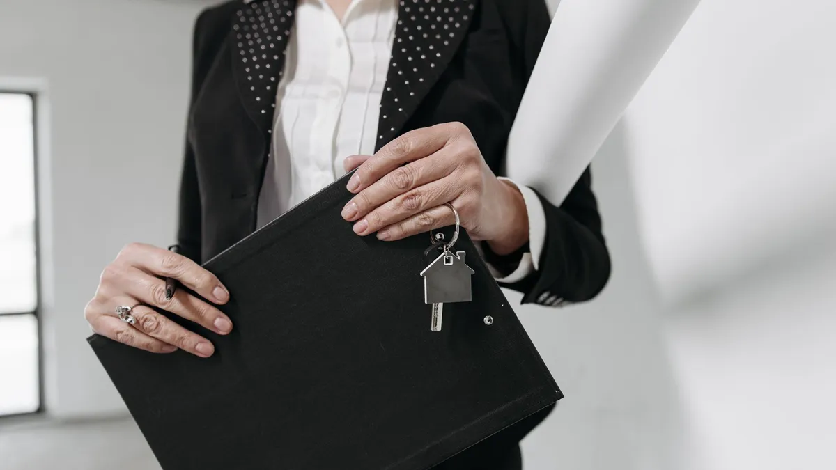 Conseiller immobilier Propriétés Privées présentant une estimation sur tablette devant une maison moderne